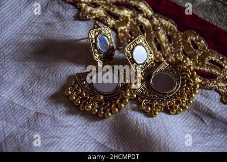 Photo de stock de beaux bijoux indiens miroir doré zumka ou boucle d'oreille sur fond blanc.bijoux traditionnels indiens tendance, se concentrer sur l'objet à Banga Banque D'Images