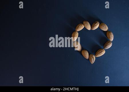 Délicieux noix d'amande sous forme de coeur sur fond bleu, papier peint pour la Saint-Valentin Banque D'Images