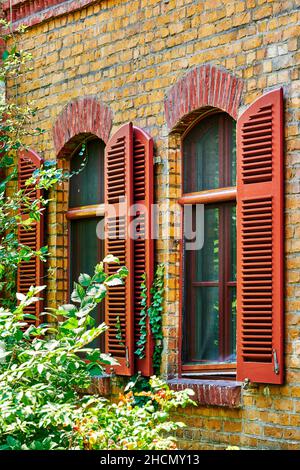 Façade d'un ancien bâtiment en briques avec volets en bois à Berlin, Allemagne. Banque D'Images