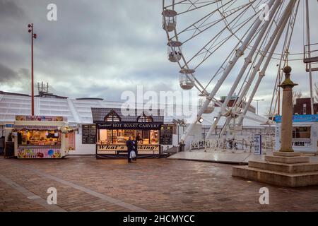 La roue lumineuse de Noël et les vendeurs de nourriture de rue font une apparence festive dans Jubilee Square.Le monument High Cross est également visible. Banque D'Images