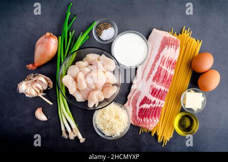 Ingrédients pour les pâtes Carbonara avec noix de Saint-Jacques poêlées : vue de dessus des noix de Saint-Jacques crues, des nouilles linguines, du bacon et d'autres ingrédients Banque D'Images