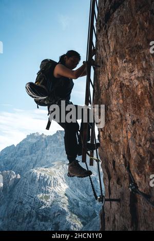 Fille monte une via ferrata lettre sur un mur massif à l'Toblinger Knoten dans les Dolomites, Italie Banque D'Images