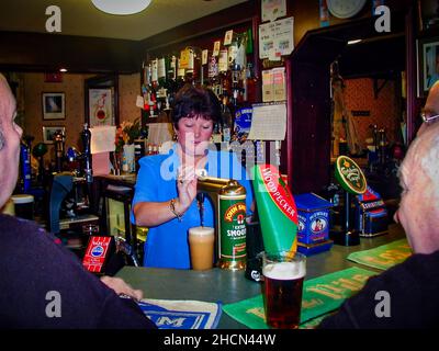 La barmaid tire une pinte de bière dans un pub anglais Banque D'Images