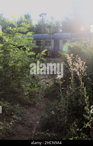 Train passant vu d'une ouverture d'une clôture au coucher du soleil Banque D'Images