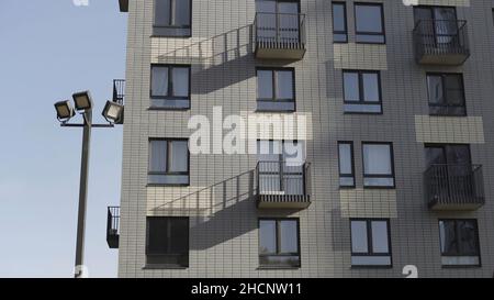 Vue de dessous du nouveau bâtiment résidentiel en briques blanches.Fragment d'une maison d'appartement en brique blanche avec balcons et lanternes de rue contre Banque D'Images