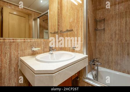 Toilettes avec lavabo en porcelaine blanche sur comptoir en marbre et baignoire en arrière-plan Banque D'Images