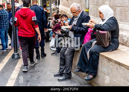 Un couple Senior manger Un plat typique de Kunafa à l'extérieur de la pâtisserie/boutique de sucreries d'Habibah, au centre-ville, Amman, Jordanie. Banque D'Images