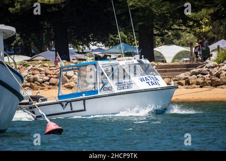 Le bateau-taxi quitte le quai au terrain de camping du bassin à Pittwater, Sydney, Australie Banque D'Images