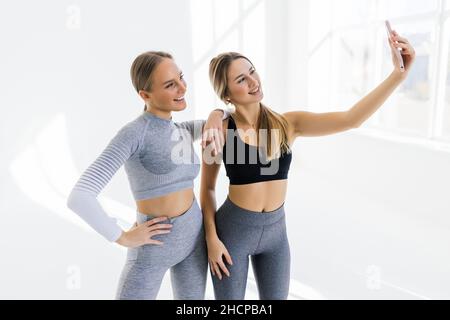 Deux femmes se rencontrent à la salle de gym, faisant le selfie photo tout en se tenant ensemble à la salle de gym Banque D'Images