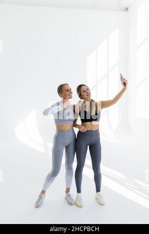 Deux femmes se rencontrent à la salle de gym, faisant le selfie photo tout en se tenant ensemble à la salle de gym Banque D'Images