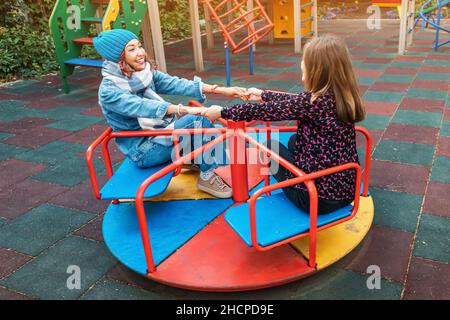 Deux amies childish Happy Woman ou adolescente s'amusent sur la mer et le carrousel sur un terrain de jeu.Concept de psychologie de la nouvelle génération et re Banque D'Images