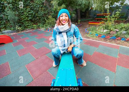 Ininfantile et childish Happy Woman ou une adolescente balance sur la seesaw.Concept de psychologie et de sociologie de la nouvelle génération et de grandir. Banque D'Images