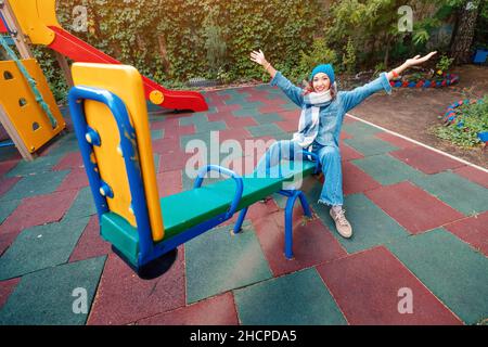 Ininfantile et childish Happy Woman ou une adolescente balance sur la seesaw.Concept de psychologie et de sociologie de la nouvelle génération et de grandir. Banque D'Images