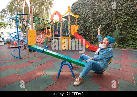 une femme infantile et puérile ou une adolescente balance sur la seesaw.Le concept de psychologie et de sociologie de la nouvelle génération et de grandir. Banque D'Images