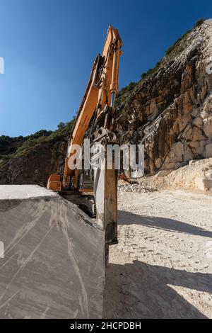 Pelle tracker orange avec le marteau dans une carrière de marbre (marbre blanc Carrare) dans les Alpes Apuanes (Alpi Apuane).Toscane, Italie, Europe. Banque D'Images