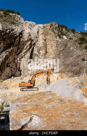 Pelle à chenilles orange avec le marteau dans une carrière, marbre blanc Carrara dans les Alpes Apuanes (Alpi Apuane - Italien).Toscane, Italie, Europe. Banque D'Images