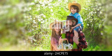 Bannière printanière avec famille heureuse.Une famille joyeuse pique-nique dans un parc.Agriculteurs familiaux travaillant dans le jardin des arbres au printemps.Père mère et enfant dans Banque D'Images