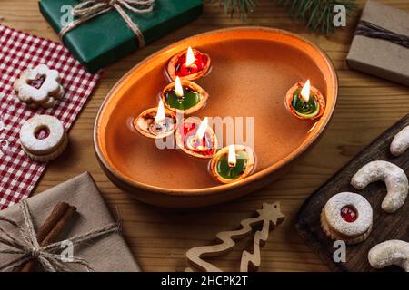 Bougies allumées en noix de muscade flottant sur l'eau.Tradition de Noël.Décoration, bonbons de noël et cadeau sur table Banque D'Images