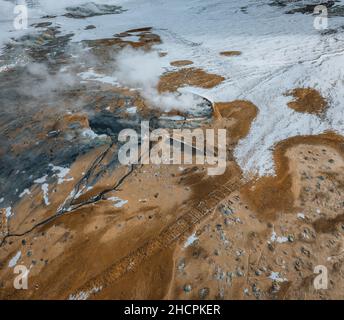 Panorama aérien de Drone avec de la vapeur chaude venant du sol.Hverir est la zone géothermique de Myvatn.Paysage couvert de neige et de sol orange. Banque D'Images