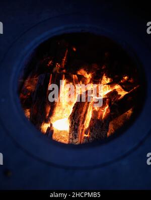 Détails avec feu de bois brûlant à l'intérieur d'un poêle en fer dans l'arrière-cour d'une maison rurale en Roumanie. Banque D'Images