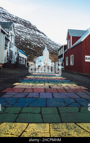 Rayures arc-en-ciel sur le trottoir menant à l'église Seydisfjordur en Islande Banque D'Images