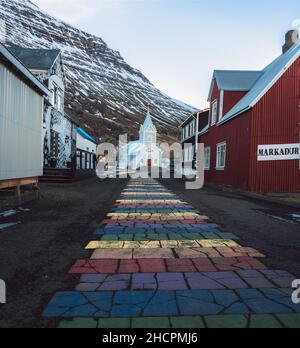 Rayures arc-en-ciel sur le trottoir menant à l'église Seydisfjordur en Islande Banque D'Images