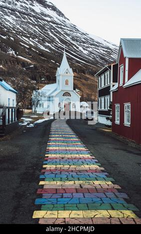 Rayures arc-en-ciel sur le trottoir menant à l'église Seydisfjordur en Islande Banque D'Images