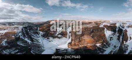 Vue aérienne par drone de la cascade de Haifoss en Islande pendant l'hiver dans les Highlands.Ciel bleu et nuages dans la neige. Banque D'Images