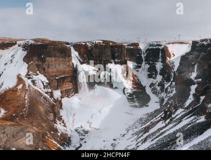 Vue aérienne par drone de la cascade de Haifoss en Islande pendant l'hiver dans les Highlands.Ciel bleu et nuages dans la neige. Banque D'Images