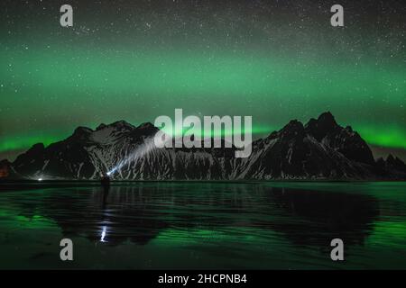 Les jeunes voyageurs se trouvent devant la chaîne de montagnes Vestahorn Stockknes avec aurora borealis et se reflètent sur la plage en Islande.L'un des plus Banque D'Images