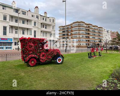 Une voiture classique couverte de coquelicots pour le jour du souvenir. Silhouettes métalliques de soldats avec des couronnes Banque D'Images