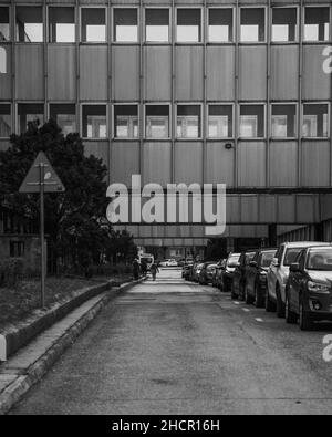 Photo en noir et blanc d'une rue avec des parkings et un bâtiment résidentiel Banque D'Images