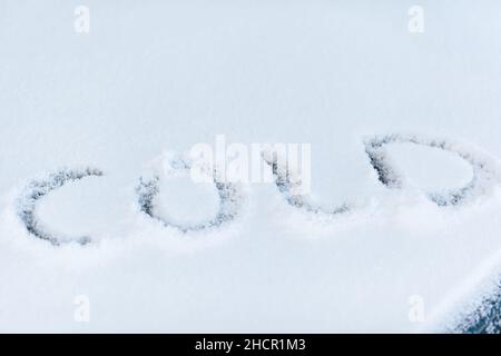 Le mot froid écrit sur un écran de voiture gelé.Froid écrit sur le pare-brise avant d'une voiture.Mot froid sur les essuie-glaces de voiture.Inscription froide sur une mousse Banque D'Images