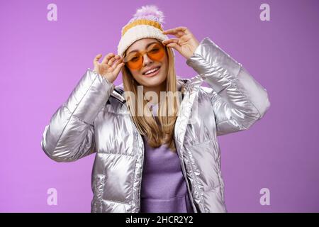 Élégant sassy audacieux blond européen fille agissant cool habillement élégant lunettes de soleil argent veste hiver chapeau contrôle cadres nez inclinaison tête souriant Banque D'Images