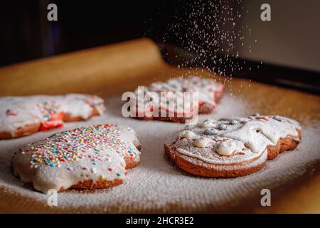 Saupoudrer de sucre glace sur les biscuits de Noël. Banque D'Images