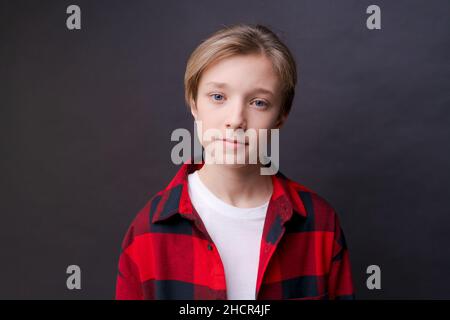 Gros plan d'un jeune homme concentré et confiant en chemise à carreaux regardant un portrait de studio d'appareil photo isolé sur fond noir de studio.Un homme millénaire réfléchi pose pour un album photo. Banque D'Images