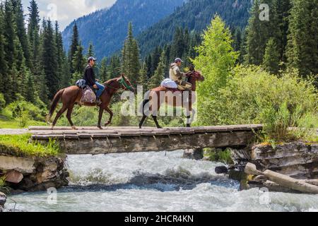 KARAKOL, KIRGHIZISTAN - 16 JUILLET 2018 : des cavaliers locaux traversent un pont au-dessus de la rivière Karakol au Kirghizistan Banque D'Images