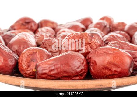 Plusieurs baies de ziziphus séchées sucrées sur un plat d'argile, en gros plan, isolées sur blanc. Banque D'Images