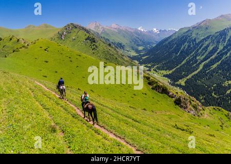 AK SU, KIRGHIZISTAN - 19 JUILLET 2018: Équitation touristique avec un guide près de la vallée d'Ak su près de Karakol, Kirghizistan Banque D'Images