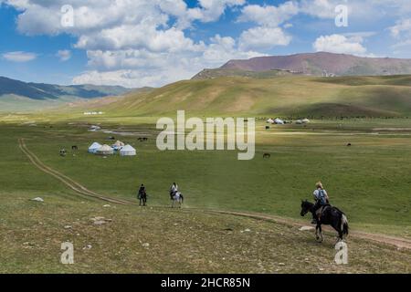 SONG KUL, KIRGHIZISTAN - 23 JUILLET 2018 : touristes sur des chevaux arrivant dans un camp de yourtes près du lac Song Kul, Kirghizistan Banque D'Images