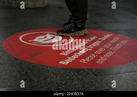 Grand cercle rond sur la plate-forme de la station Marienplatz à Munich avec une demande de couvrir la bouche et le nez.Les pieds des passagers sont visibles. Banque D'Images