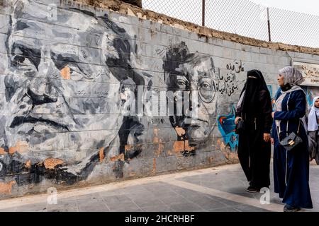 Un groupe de femmes marchent devant Une murale dans le centre-ville d'Amman, Amman, Jordanie. Banque D'Images