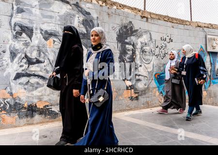 Un groupe de femmes marchent devant Une murale dans le centre-ville d'Amman, Amman, Jordanie. Banque D'Images