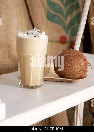 Latte à la noix de coco dans un grand verre et noix de coco sur une balançoire dans un café.Gros plan. Banque D'Images