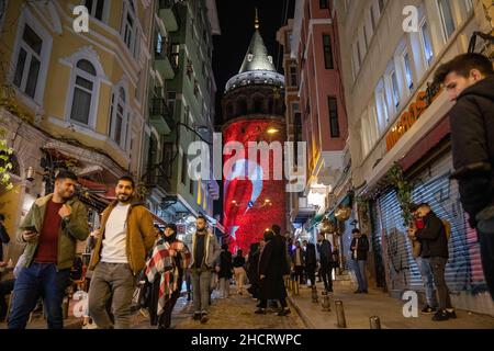 Istanbul, Turquie.31st décembre 2021.31 décembre 2021: 31 décembre 2021 à Istanbul, Turquie: Drapeau turc projeté sur la tour historique de Galata et les gens passant par la rue.Scènes de personnes des rues d'Istanbul le jour de l'an.(Credit image: © Tolga Ildun/ZUMA Press Wire) Credit: ZUMA Press, Inc./Alamy Live News Banque D'Images