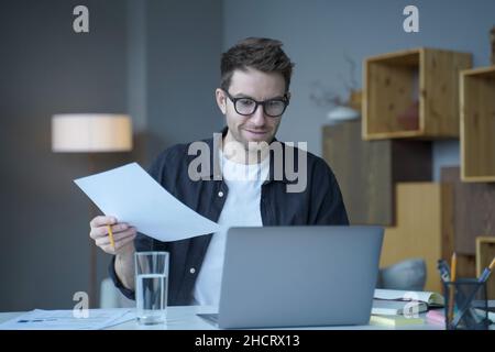 Confiant homme positif conseiller financier dans les lunettes travaille à distance en ligne au bureau à domicile moderne Banque D'Images