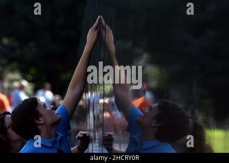 Les visiteurs du Mémorial des anciens combattants du Vietnam à Washington, D.C., touchent les noms de ceux qui sont morts dans la guerre qui sont gravés sur la face en pierre polie du Mémorial.Le mémorial a été conçu par Maya Lin. Banque D'Images