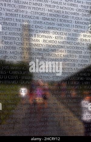 Le visage du Vietnam Veterans Memorial à Washington, D.C. le mémorial, qui a été conçu par Maya Lin, comprend des noms sculptés de chacun des plus de 55 000 morts de guerre aux États-Unis.Le monument de Washington et les visiteurs du site commémoratif sont visibles sur la surface réfléchie du monument commémoratif. Banque D'Images