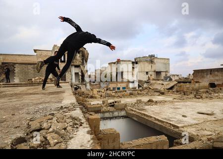 Idlib, Syrie.31st décembre 2021.Un jeune homme démontre ses compétences Parkour entre les bâtiments détruits par les frappes aériennes russes.Crédit : SOPA Images Limited/Alamy Live News Banque D'Images