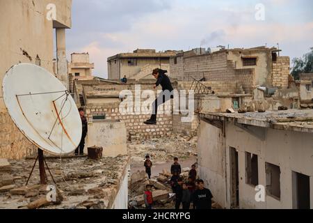 Idlib, Syrie.31st décembre 2021.Un jeune homme démontre ses compétences Parkour entre les bâtiments détruits par les frappes aériennes russes.Crédit : SOPA Images Limited/Alamy Live News Banque D'Images